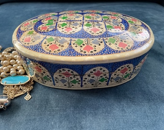 May include: An oval-shaped decorative box with a blue and white floral pattern. The box is made of papier-mâché and has a hinged lid.
