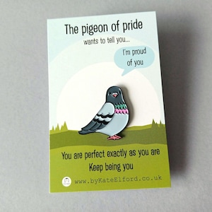 A pin badge of a cartoon pigeon with a speech bubble saying "I'm proud of you." The badge is on a card with the text "The pigeon of pride wants to tell you..." and "You are perfect exactly as you are. Keep being you."