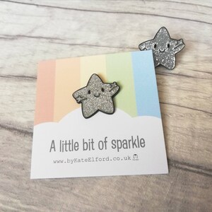 May include: Two silver glitter star-shaped pins with smiling faces. One pin is attached to a card with a rainbow background and the text "A little bit of sparkle". The website address www.byKateElford.co.uk is also visible.