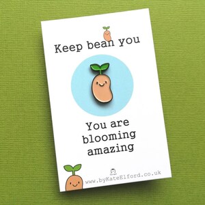 May include: A white card with the text "Keep bean you" and a cartoon bean sprout with a smiling face. The card also says "You are blooming amazing" and includes a website address.