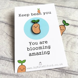 May include: White card with the text "Keep bean you, you are blooming amazing" and a cartoon bean sprout with a smiling face. The card has a website address at the bottom: www.byKateElford.co.uk