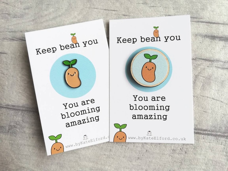 May include: Two white cards with blue accents and a cartoon bean sprout illustration. The text on the cards reads "Keep bean you. You are blooming amazing." and includes the website address "www.byKateElford.co.uk".