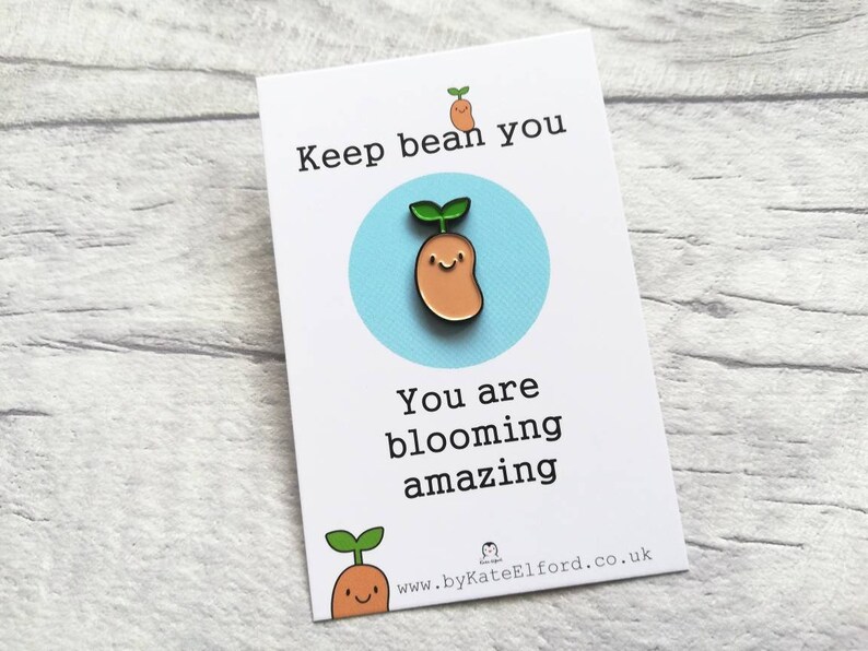 May include: A white card with the text "Keep bean you, you are blooming amazing" and a cartoon bean sprout with a smiling face. The card also includes the website address "www.byKateElford.co.uk".