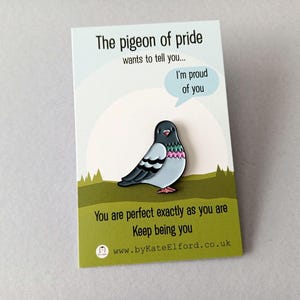 A colourful pigeon pin on a card. The card reads "The pigeon of pride wants to tell you... I'm proud of you." and "You are perfect exactly as you are." The pin is a cartoon design with a speech bubble.