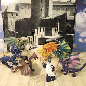 May include: A collection of toy dragons in various colors, including blue, green, yellow, orange, and purple, with detailed wings and scales. A wizard figurine stands among them, holding a staff. The background features a castle scene.