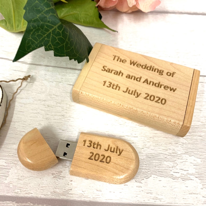 May include: A wooden USB drive in the shape of an oval, with the text "13th July 2020" engraved on it. The drive is open, revealing the USB connector. The drive is in a wooden box with the text "The Wedding of Sarah and Andrew 13th July 2020" engraved on it.