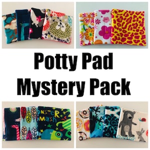 May include: A set of six colourful and patterned potty pads. The pads are made of soft fleece and feature various designs, including animals, flowers, and geometric patterns. The pads are labelled "Potty Pad Mystery Pack".