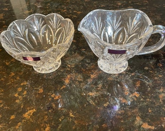 May include: Two clear glass bowls with intricate cut designs. The bowl on the left is round and the bowl on the right is heart-shaped with a handle.