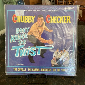 May include: A vintage vinyl record album cover featuring Chubby Checker with the title "Don't Knock The Twist". The album cover is blue and purple with a picture of Chubby Checker dancing. The album also features The Dovells, The Carroll Brothers, and Dee Dee Sharp.