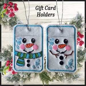 May include: Two white gift card holders with snowman faces, black eyes, orange carrot noses, and pink cheeks. One has a blue and green scarf, the other has brown stick arms. The text "Gift Card Holders" is at the top.