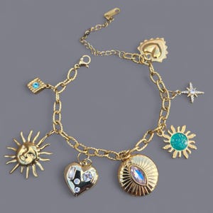 May include: Gold-toned charm bracelet featuring celestial and heart-shaped charms. The bracelet includes a sun with a face, a heart with clear stones, a star, and a turquoise-centered sun. The chain is a textured link design.