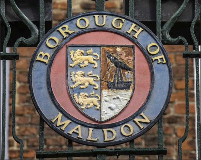 Peut inclure: Un panneau circulaire bleu et rouge avec le texte "Borough of Maldon" en lettres blanches. Le panneau pr&eacute;sente un blason avec un navire et trois lions.