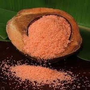 May include: A close-up of a bowl of pink Himalayan salt, a type of rock salt, in a wooden bowl. The salt is coarse and granular.