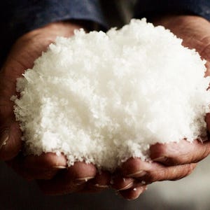 Peut inclure: Des mains tenant une grande quantit&eacute; de sel marin blanc et floconneux.