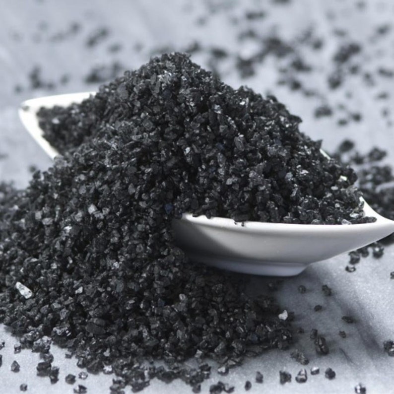 May include: A close-up of black Hawaiian salt in a white bowl. The salt is coarse and has a dark, almost black color.