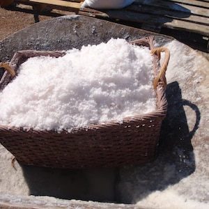 May include: A wicker basket filled with white salt crystals. The basket is sitting in a large, gray, concrete container.