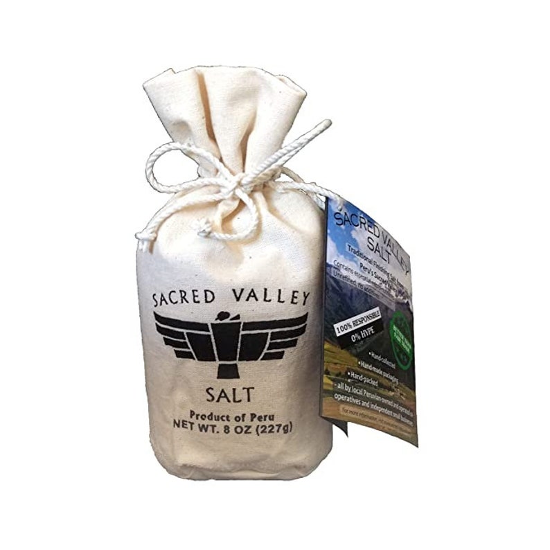 May include: A white cotton bag filled with salt from the Sacred Valley of Peru. The bag is tied with a white string and has a black label with the words "Sacred Valley Salt" and a black and white image of a condor. The label also states "Product of Peru" and "Net Wt. 8 oz (227g)".