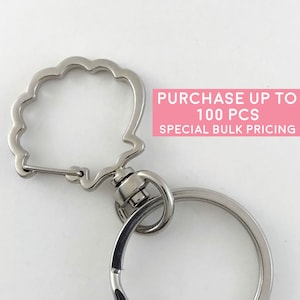 May include: A silver-colored keychain with a decorative, scalloped-edge clasp and a circular key ring. The text "PURCHASE UP TO 100 PCS SPECIAL BULK PRICING" is visible in the image. The keychain is designed for holding keys.