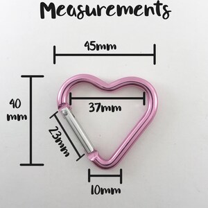 May include: Pink heart-shaped carabiner with measurements: 45mm, 40mm, 37mm, 23mm, and 10mm.