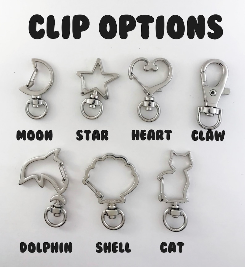 May include: A set of 9 silver metal keychains with different shapes, including a moon, star, heart, claw, dolphin, shell, and cat. The keychains are labeled with their corresponding shapes.