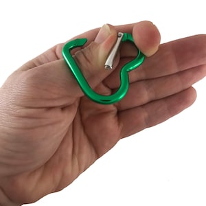 May include: A green metal carabiner with a heart shape. The carabiner is open and ready to be used.