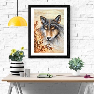 Könnte beinhalten: Ein Aquarellbild eines Wolfskopfes mit einem weichen, verträumten Hintergrund in Braun- und Orangetönen. Das Fell des Wolfes ist eine Mischung aus Grau und Braun, und seine Augen sind tiefbraun. Das Bild ist in Schwarz gerahmt.