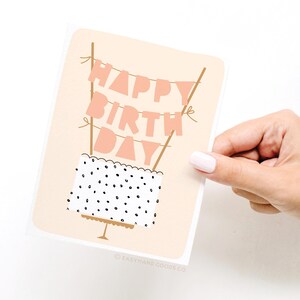 A hand holding a birthday card with the text "Happy Birthday Day" written on it.