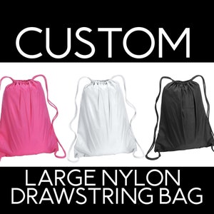 May include: Three drawstring bags in pink, white, and black. The bags are made of nylon and have a large capacity. The text "CUSTOM LARGE NYLON DRAWSTRING BAG" is displayed below the bags.