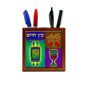 May include: A wooden desk organizer with a colorful design featuring a tree, a goblet, a Torah scroll, and the Hebrew text "עץ חיים" (Tree of Life).