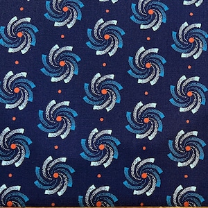 May include: Dark navy blue fabric with a repeating pattern of stylized spiral designs in shades of blue, white, and orange. The fabric has a ruler along the bottom edge, showing measurements in inches.