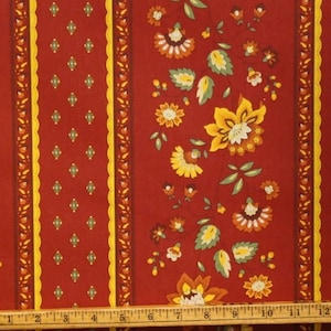 May include: Red fabric with a repeating pattern of yellow and orange flowers and green leaves. The fabric has a yellow and brown striped border.