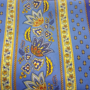 May include: Blue and yellow striped fabric with a floral pattern. The fabric has a repeating pattern of flowers and leaves in shades of blue, yellow, and orange. The fabric is made of cotton and is suitable for upholstery, curtains, and other home decor projects.