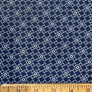 May include: A navy blue fabric with a white geometric pattern of interlocking circles and squares. A ruler is included for scale.