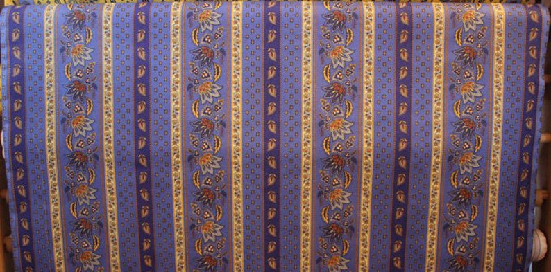 May include: Blue and yellow striped fabric with a floral pattern. The fabric has a repeating pattern of small flowers and leaves.