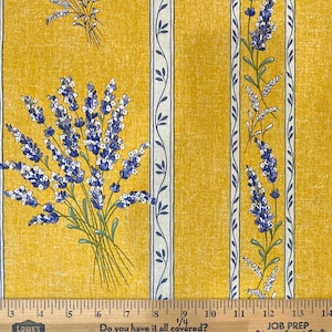 May include: Yellow fabric with a white and blue striped pattern. The fabric has a floral design with lavender flowers. The fabric is measured with a ruler.