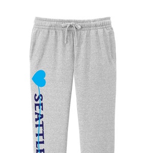 May include: Gray sweatpants with a blue heart and the word "SEATTLE" printed on the left leg.