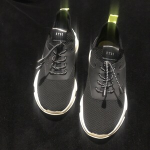 May include: Pair of black athletic sneakers with white soles. The sneakers have a mesh upper, black laces, and the text "NY88" on the tongue. The shoes are designed for running or casual wear.
