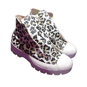 May include: A pair of high-top sneakers with a white base and a leopard print design. The shoes have a thick white sole with a textured tread.