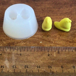 May include: A clear silicone mold with two cavities shaped like small birds. Two yellow plastic birds are next to the mold, one is slightly larger than the other.