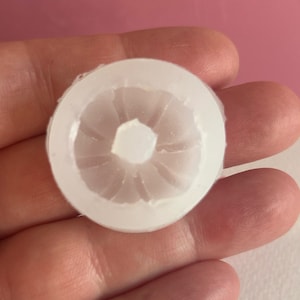 May include: White plastic mold with a circular design, resembling a flower.