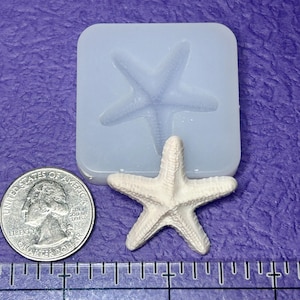 May include: A white starfish next to a quarter and a blue silicone mold of a starfish. The starfish is approximately 2 inches in diameter. The mold is square with rounded corners. The background is purple.
