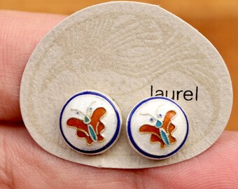 Könnte beinhalten: Ein Paar silberne Schmetterlings-Ohrringe mit weißer, orangefarbener, blauer und grüner Emaille. Die Ohrringe befinden sich auf einer weißen Karte mit dem aufgedruckten Wort "laurel".