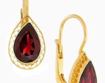May include: A pair of gold earrings with a teardrop-shaped red gemstone set in a delicate filigree design.
