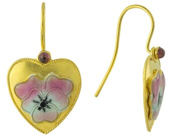 May include: Gold-tone heart-shaped earrings with a floral design. The earrings feature a pink, white, and black flower on a gold background. A small, round, red gemstone is set at the top of each earring.