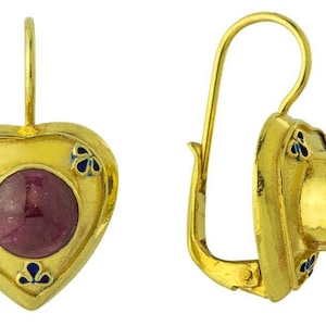 May include: A pair of gold heart-shaped earrings with ruby red stones set in the center. The earrings have a blue enamel design around the stones.