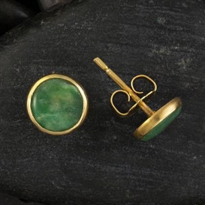 May include: A pair of gold stud earrings with round green jade stones.