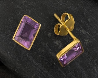 May include: A pair of gold earrings with purple amethyst stones. The stones are rectangular and have a faceted cut.