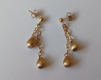 May include: Gold drop earrings with two teardrop-shaped charms hanging from a chain.