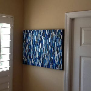 May include: Abstract painting with a blue, white and grey colour scheme. The painting is made up of many small, geometric shapes.