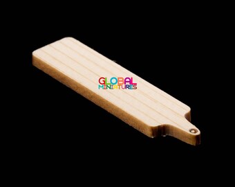 May include: A miniature wooden cutting board with a light brown color and a slightly rounded edge. The board is approximately 10 inches long and 2 inches wide.